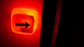 Rotleuchtende Lampe mit aufgemaltem Pfeil, der in Richtung einer geöffneten Tür zeigt (Foto: villain-jan l photocase.com)