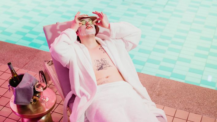 Musiker Chapo102 liegt auf einem Sonnenstuhl, hat eine Beauty-Maske mit Gurken im Gesicht und neben sich ein Glas Wein stehen. | Foto: Robert Lüthje