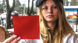Eine junge Frau zeigt in die Kamera eine rote Karte. | Quelle: IMAGO / Rolf Kremming