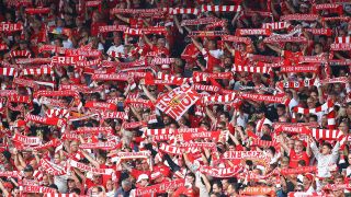Fans des 1. FC Union Berlin stehen auf der Tribüne und halten rot-weiße Fan-Schals in die Luft (Quelle: IMAGO / Jan Huebner)
