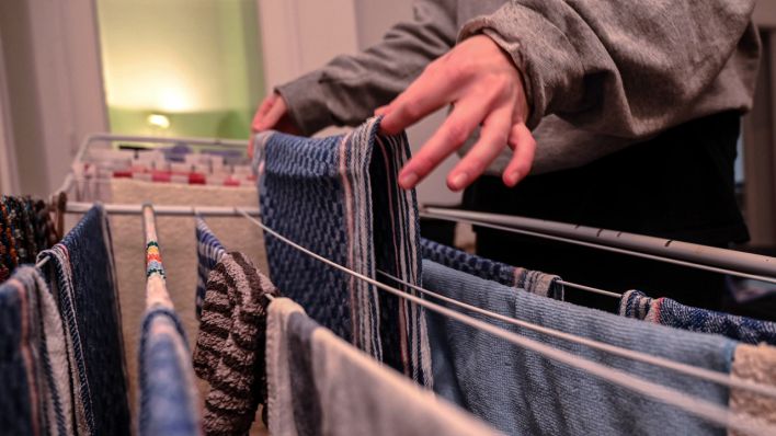 Ein voller Wäscheständer, auf den noch ein Küchenhandtuch gehängt wird. (Quelle: IMAGO | Funke Foto Services) Ein voller Wäscheständer, auf den noch ein Küchenhandtuch gehängt wird. (Quelle: IMAGO | Funke Foto Services)
