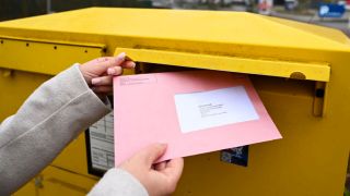 Jemand wirft den Wahlbrief in den Briefkasten (Quelle: Picture Alliance | Epd bild | Heike Lyding)