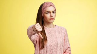 Ein junge Frau, die den Daumen nach unten zeigt (Quelle: IMAGO | Zoonar)