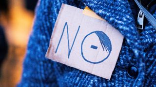 Eine Person trägt ein Pappschild an ihrer Jacke, um gegen rechts zu demonstrieren. (Quelle: IMAGO | Noah Wedel)