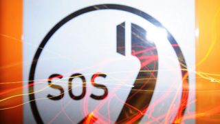 SOS-Telefon-Symbol, auf dem sich bunte Lichter spiegeln (Foto: himberry l photocase.com)