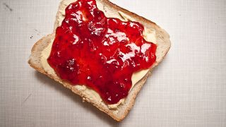 Eine Toastbrot-Scheibe mit Butter und roter Marmelade (Foto: suze l photocase.com)